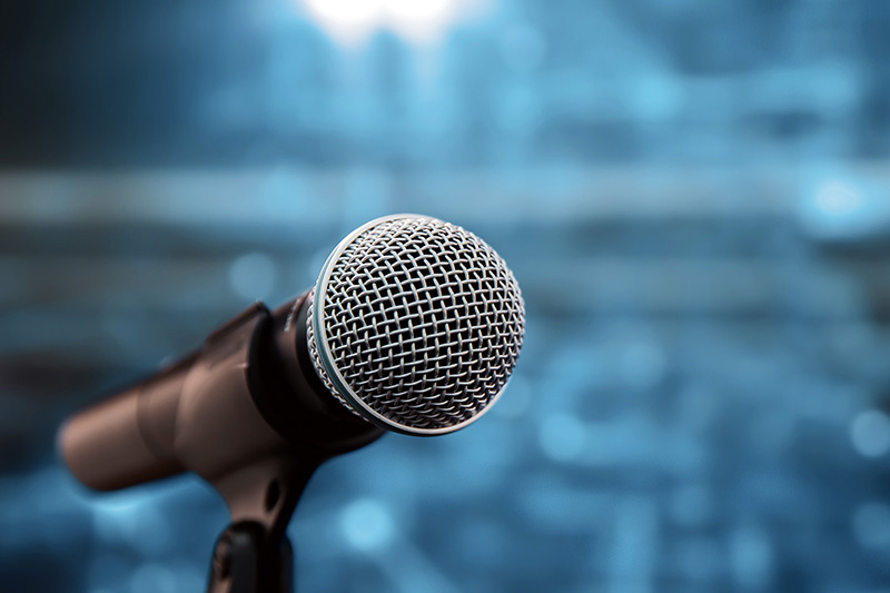 A microphone in a stand with a blue background.